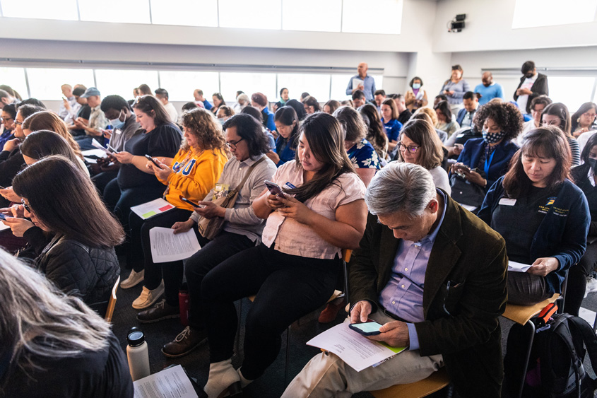 Participants sitting in a room together taking a survery during the summit.